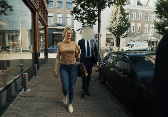 Hire a bodyguard in Amsterdam | Infinite Risks International | A stylish woman walking down the street in a city, wearing sunglasses and a brown top.