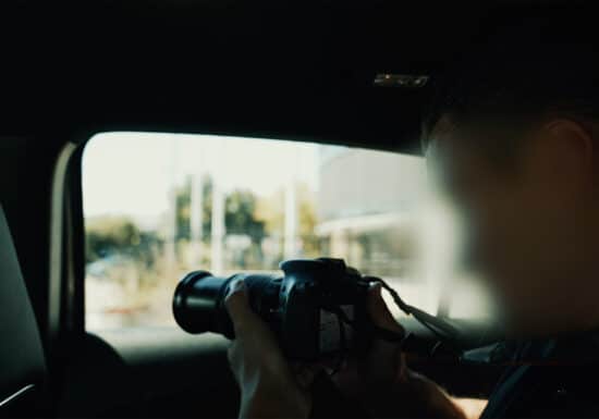 Finding Missing Persons | Person holding a DSLR camera inside a car, aiming through the window.
