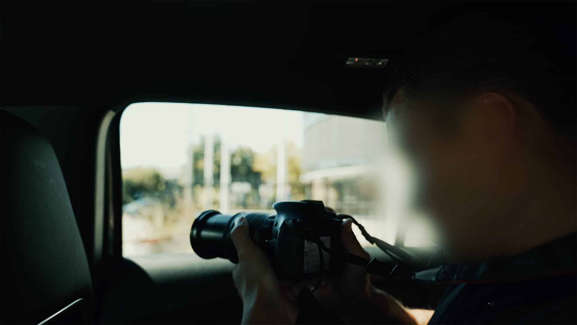 Finding Missing Persons | Person holding a DSLR camera inside a car, aiming through the window.