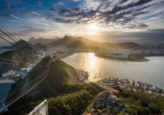 Bodyguard Services in Brazil. A view of Rio de Janeiro from above, with mountains, bay, and city under the sunset.