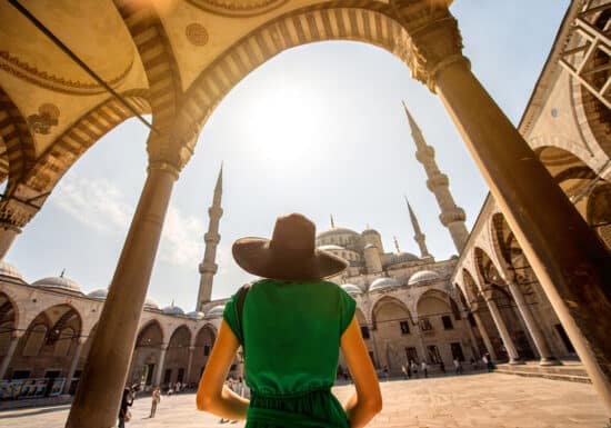 Bodyguard Services in Turkey. A woman in a wide-brimmed hat gazes at the Blue Mosque's towering minarets from the courtyard.