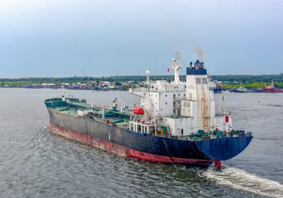 Anti-Piracy Training. Cargo ship sailing on a river near a port.