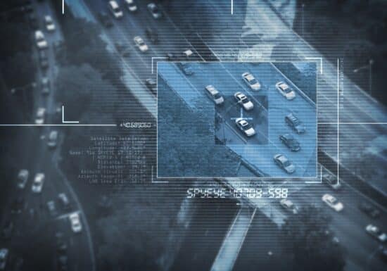 Is My Phone Tapped? Aerial surveillance view showing vehicles on a highway, with a digital overlay providing data and tracking details.