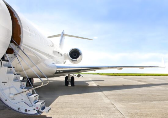 Private Jet Security Services. A sleek private jet parked on an empty runway with a bright blue sky overhead.