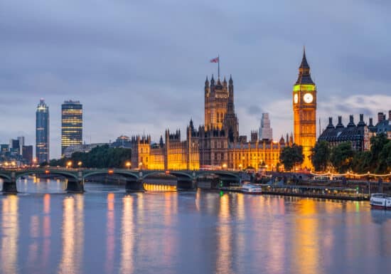 Bodyguard Services in London. Night scene of a famous landmark and bridge reflecting lights on a river.