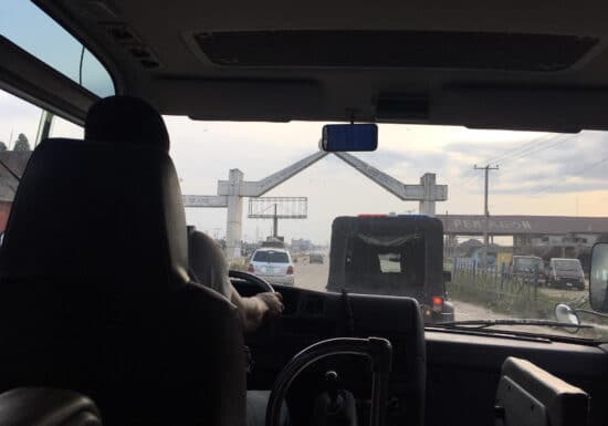 Armed vs Unarmed Security Services. View from inside a vehicle, driving towards an arched gate.