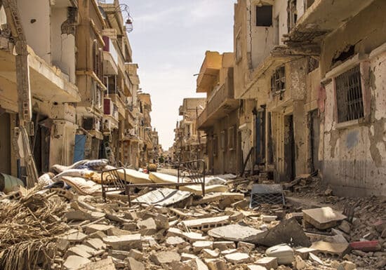 Media Security. A war-torn street with rubble and destroyed buildings on both sides.