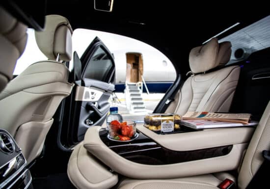 Luxury Travel Protection. Luxurious car interior with snacks, water, and a private jet in the background