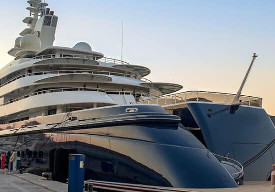 Superyacht Security. A large luxury yacht docked at a marina at sunset.