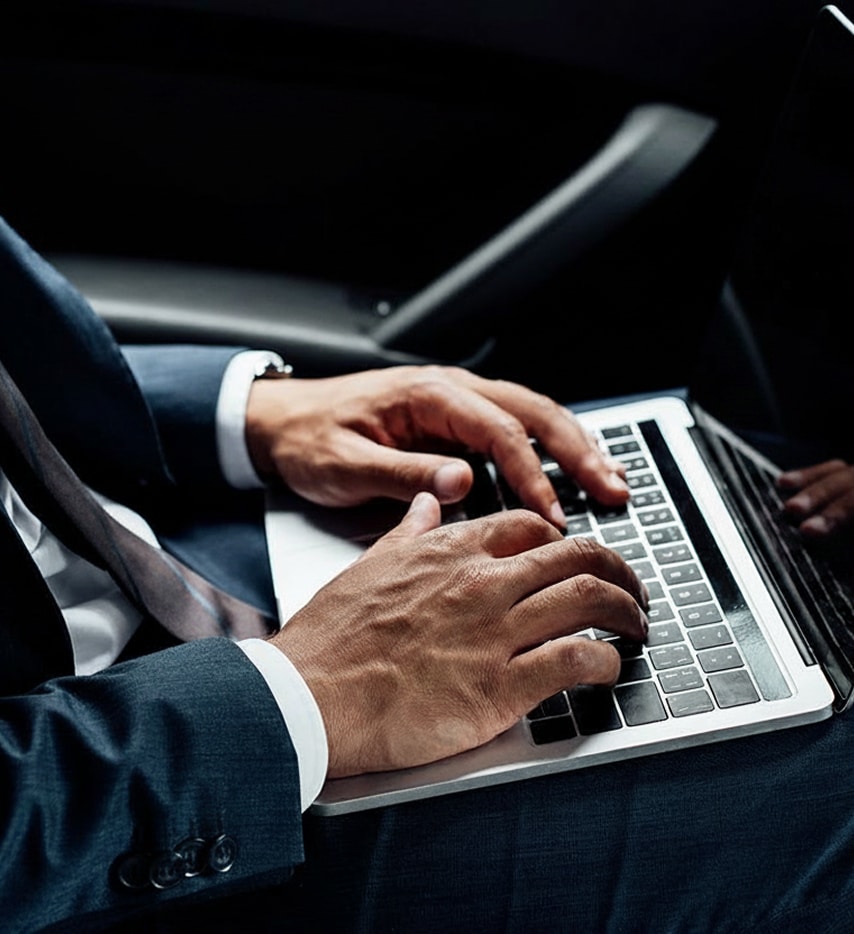 Hands typing on a laptop in a dark car